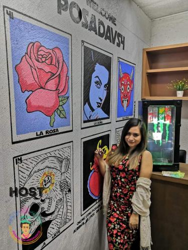 a woman standing in front of a wall with art at Posada Vs4 Aeropuerto in Mexico City