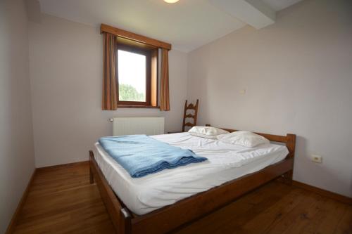 a bedroom with a bed with a blue blanket on it at Achouffe - LACHENAL in Achouffe