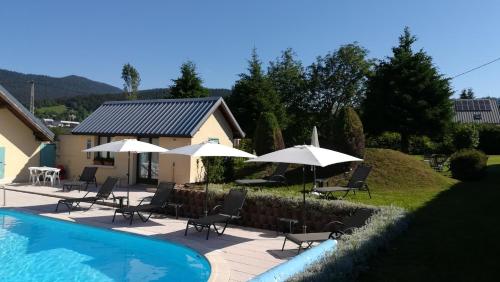 a swimming pool with chairs and umbrellas at Hôtel Restaurant Les Tilleuls in Autrans