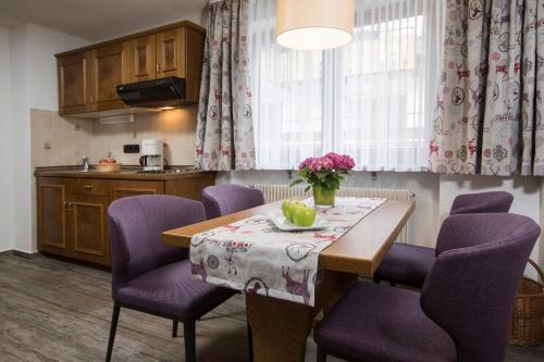 a kitchen with a table with purple chairs and flowers on it at Landhaus Sackmann in Baiersbronn