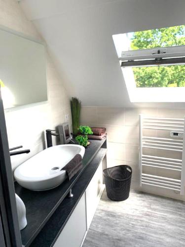 La salle de bains est pourvue d'une grande baignoire blanche et d'un lavabo. dans l'établissement Logement entier Saint Malo vue mer, proche FERRY, commerces et plage Solidor 50 m, à Saint-Malo