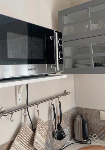 a kitchen with a microwave and hanging utensils at Ferienwohnungen Weise im Lausitzer-Seenland in Großräschen