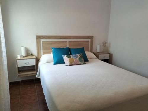 ein Schlafzimmer mit einem großen weißen Bett mit blauen Kissen in der Unterkunft APARTAMENTO EN URBANIZACIÓN AL-ÁNDALUs CERCA DE LA PLAYA DE LA BARROSA in Chiclana de la Frontera