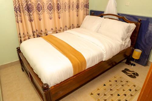 Bonaventure Apartment في كيزيمو: غرفة نوم بسرير وستارة وملاصق للسرير لديهم مشاكل في التعامل