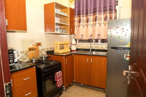 cocina con armarios de madera y nevera de acero inoxidable en Bonaventure Apartment, en Kisumu