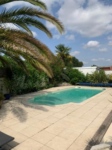 a swimming pool with a palm tree next to it at Chambre cosy indépendante dans jardin verdoyant. in Le Bouscat