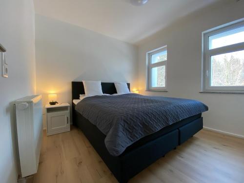 um quarto com uma cama grande e 2 janelas em Ferienhaus Bimmelbahn 2 em Olbersdorf
