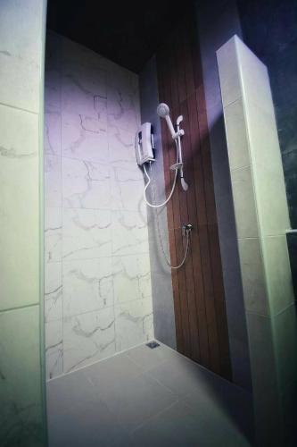 a shower in a bathroom with a stone wall at บ้านน่านอน in Uthai Thani