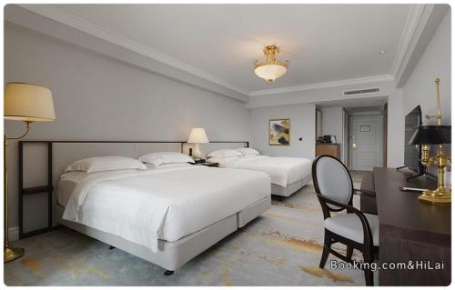 a bedroom with two beds and a desk and a chair at Grand Hi Lai Hotel in Kaohsiung