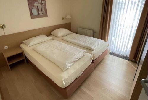 Schlafzimmer mit einem Bett mit weißer Bettwäsche in der Unterkunft Haus Kiek Ut Apartment 24 in Timmendorfer Strand