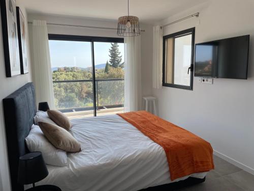 une chambre avec un lit et une grande fenêtre dans l'établissement Villa Marcaléone Corse du Sud, à Cirendinu