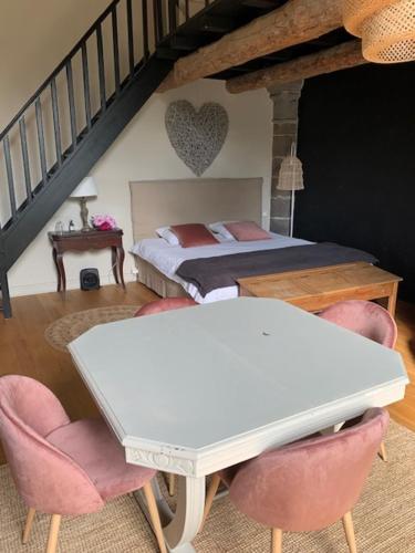 a bedroom with a bed and a table and chairs at Chambres et maisons d'hôtes du Prieuré de la Bajasse - Le 1150 in Vieille-Brioude