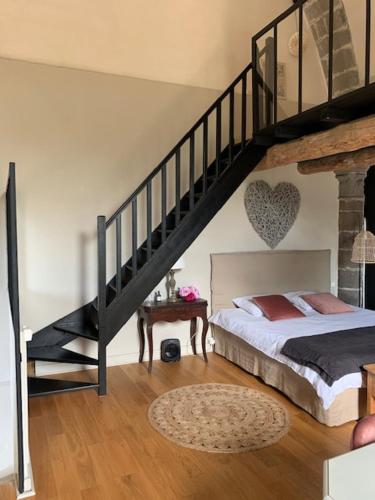 a bedroom with a bed and a stair case at Chambres et maisons d'hôtes du Prieuré de la Bajasse - Le 1150 in Vieille-Brioude