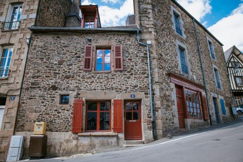 an old stone building with red doors and windows at maison quartier médiéval au pied du château FOUGERES in Fougères