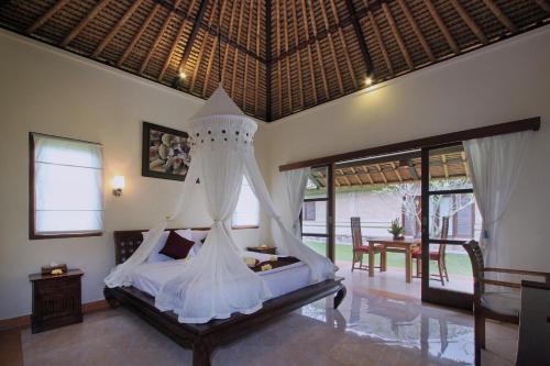 - une chambre avec un lit doté de draps et de rideaux blancs dans l'établissement Chili Ubud Cottage, à Ubud