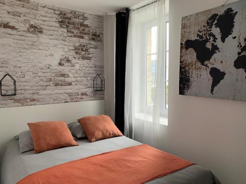 Cama en habitación con pared de ladrillo en Le petit loft - Studio - WIFI - Coeur de ville - Parking en Pont-lʼAbbé