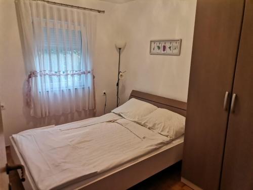 a bedroom with a bed and a window with white sheets at Apartment Dragica in Kornić
