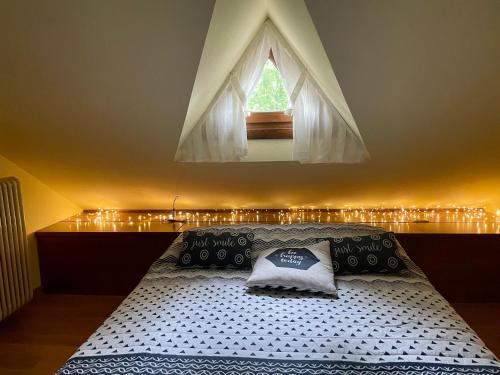 a bedroom with a bed with a window and lights at Attico CB Camona - Gallio in Gallio