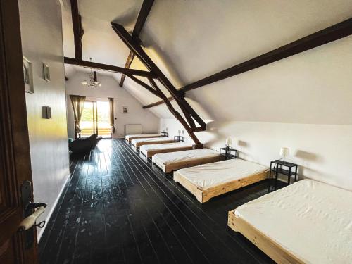 a row of beds in a room with wooden floors at Villa festive HOMAZING piscine privée 1h de Paris in Chantecoq