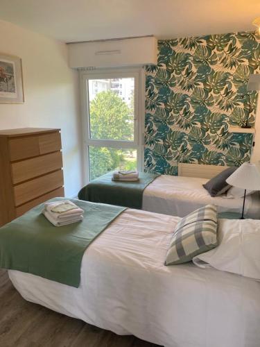 deux lits dans une chambre d'hôtel avec une fenêtre dans l'établissement Chez Tata Emma, à Annecy