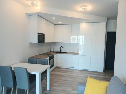 a kitchen with white cabinets and a table and chairs at AJP Nova3 Lux Apartament in Szczecin