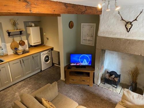ein Wohnzimmer mit einem TV und einem Kamin in der Unterkunft Calderside Cottage (2 BDR Central Hebden Bridge) in Hebden Bridge