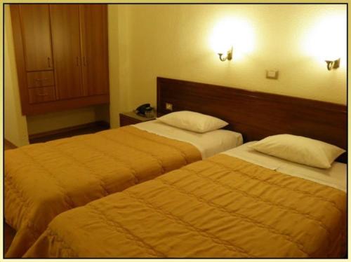 a hotel room with two beds and a cabinet at Hotel Meletiou in Thiva