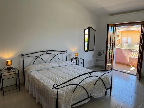 1 dormitorio con 1 cama y puerta corredera de cristal en Casa Vacanze Costa Ovest, en Terralba