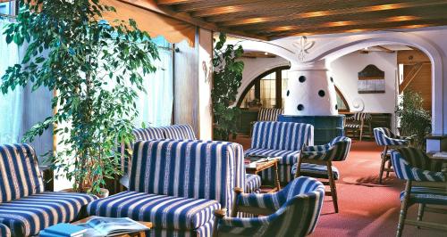 a group of chairs in a room with a fireplace at Hotel Miramonti Corvara in Corvara in Badia
