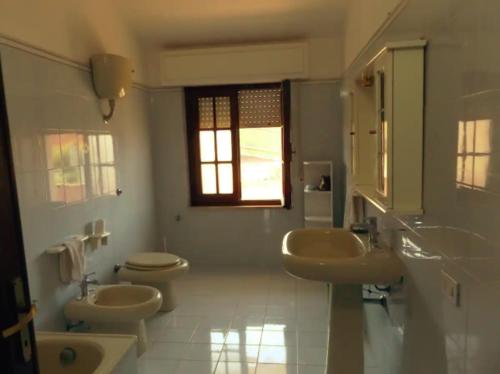 baño con 2 lavabos, aseo y ventana en Casa Vacanze Costa Ovest, en Terralba