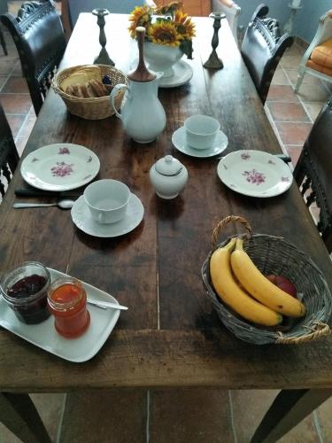 une table en bois avec des assiettes et un panier de bananes dans l'établissement La tanière, à Champs Sur Tarentaine