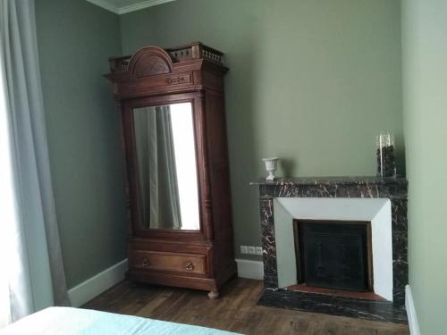 a room with a fireplace with a mirror and a dresser at La tanière in Champs Sur Tarentaine