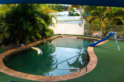 a swimming pool with a slide in the water at Kennedy Drive Boutique Motel - Close To City Centre & Airport in Tweed Heads
