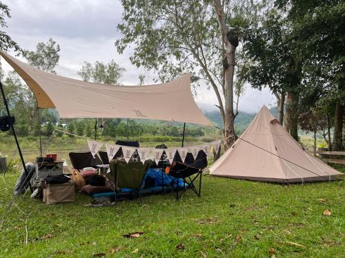 a group of chairs and a tent in the grass at ไร่นุชชม รีสอร์ทเขาค้อ in Ban Non Na Yao
