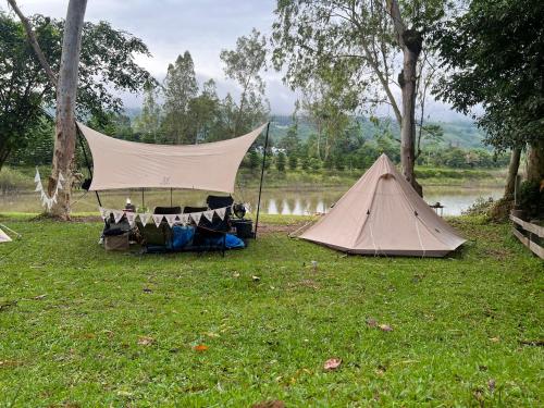 two tents sitting in the grass next to a lake at ไร่นุชชม รีสอร์ทเขาค้อ in Ban Non Na Yao