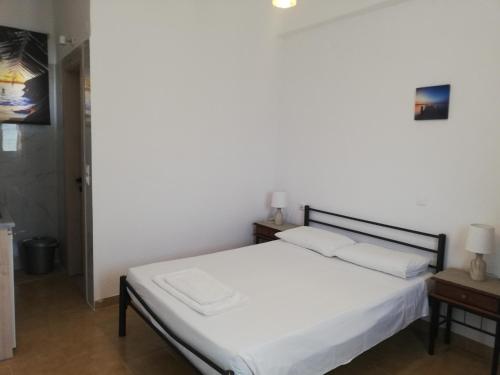 a bedroom with a white bed and a table at Anestis Studios in Agios Georgios