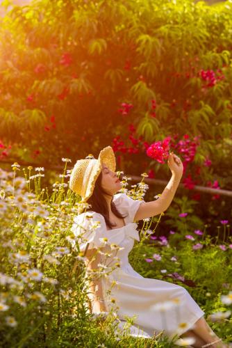 a woman is sitting in a field of flowers at H'mong Cổ Trấn Sapa Homestay & Restaurant in Sa Pa