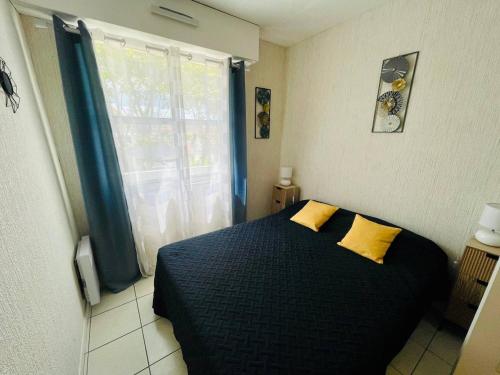 - une chambre avec un lit noir et 2 oreillers jaunes dans l'établissement Appartement T2 à Arcachon – 400m de la Plage, Terrasse, Parking, Résidence de Standing - FR-1-433-78, à Arcachon