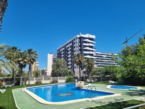 a swimming pool in a park with a tall building at Apartamento con vistas al mar in Alicante