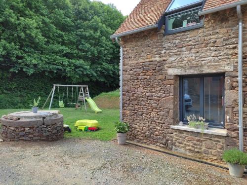 a stone house with a playground in the yard at Chambre d'hôtes in La Bazoge