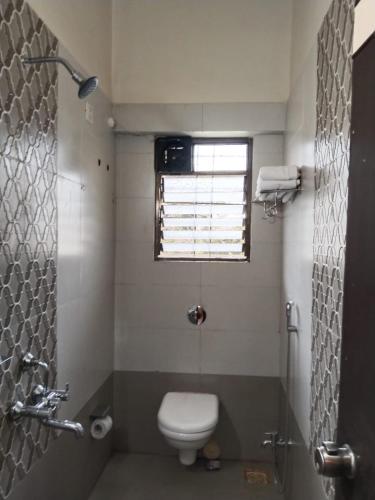 a bathroom with a toilet and a window at Cocorico Beach Resort in Dapoli
