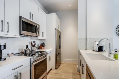 a kitchen with white cabinets and a stainless steel refrigerator at The Heart of Naples in Naples