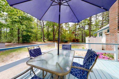 a table and chairs with an umbrella on a deck at Lake House Retreat in Ossipee