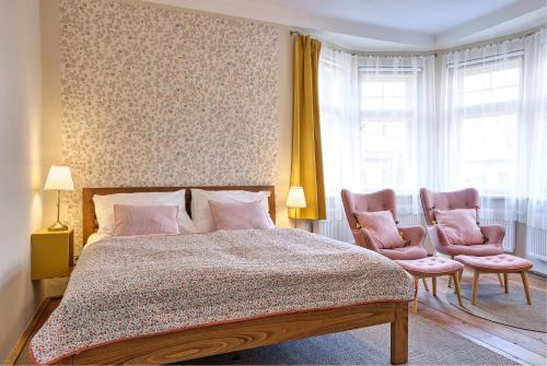 um quarto com uma cama e 2 cadeiras cor-de-rosa em Vila Betula em Nové Město na Moravě