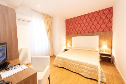 a bedroom with a bed and a desk and a television at Albergo Rossini 1936 - Small & Charming in Bologna