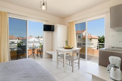 a bedroom with a bed and a kitchen with large windows at Eugenia Studios & Apartments in Ialyssos