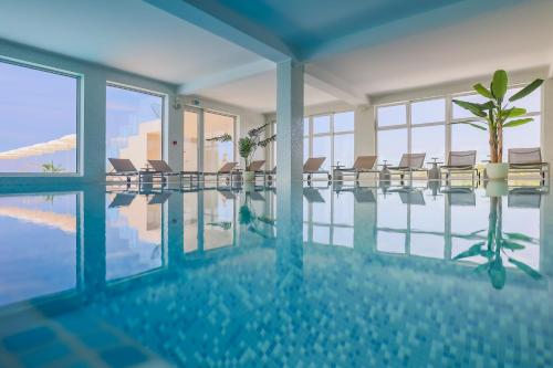 a swimming pool with chairs in a building at Hotel In Excelsis in Novalja