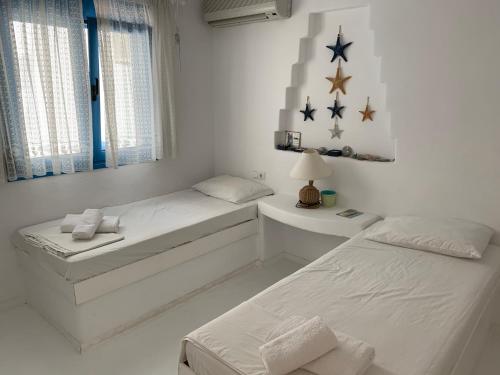 duas camas num quarto branco com estrelas na parede em Blue Sea Villa & Apartments em Makry Gialos