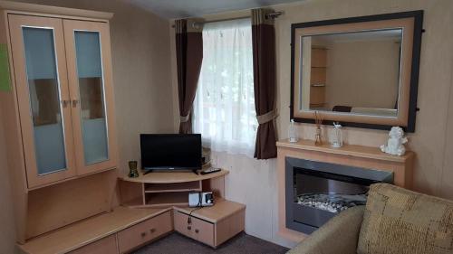 a living room with a television and a fireplace at Urocza Przystan in Kiemiany