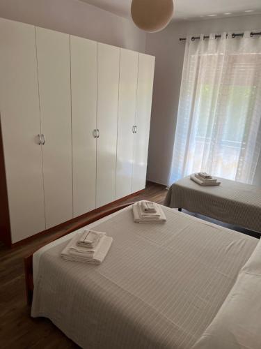 um quarto com 2 camas e armários brancos e uma janela em Appartamento Mela ad Alba, cuore delle Langhe em Alba